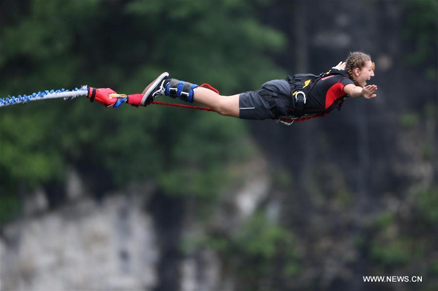 An enthusiast goes bungee jumping from Zhangjiajie Grand Canyon\'s glass-bottom bridge, during a challenge in Zhangjiajie scenic spot, central China\'s Hunan Province, May 26, 2018. Enthusiasts from Russia, Australia, Britain and other countries and regions participated in the challenge on Saturday. (Xinhua/Zhou Guoqiang)