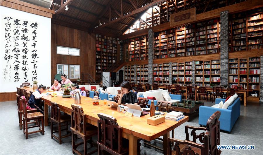 Students of Miaoqian Village study at the library in a hostel in Moganshan Town in Deqing County, east China\'s Zhejiang Province, May 29, 2018. The owner of the hostel Zhu Jindong, who worked in publishing, founded the hostel in 2015. The library collecting about 20,000 books in the hostel made it famous and attracted many tourists. (Xinhua/Weng Xinyang)