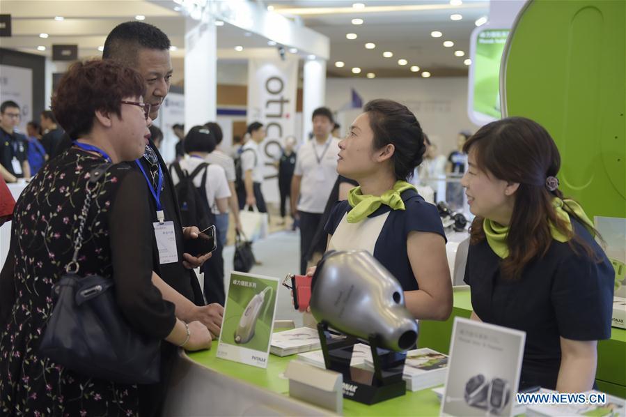 A staff member (2nd, R) answers visitors\' inquiry at the 2018 2018 Beijing International Audiology Conference in Beijing, capital of China, June 2, 2018.The 2018 Beijing International Audiology Conference kicked off here Saturday. (Xinhua/Lu Peng)