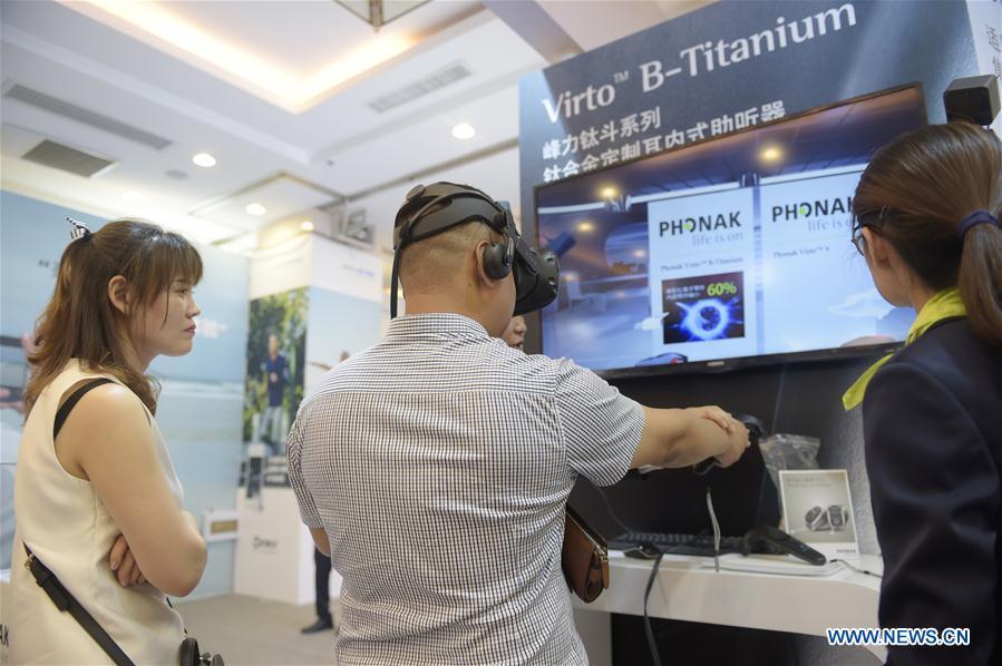 A visitor (front, R) experiences a hearing aid equipment with a VR device at the 2018 2018 Beijing International Audiology Conference in Beijing, capital of China, June 2, 2018. The 2018 Beijing International Audiology Conference kicked off here Saturday. (Xinhua/Lu Peng)
