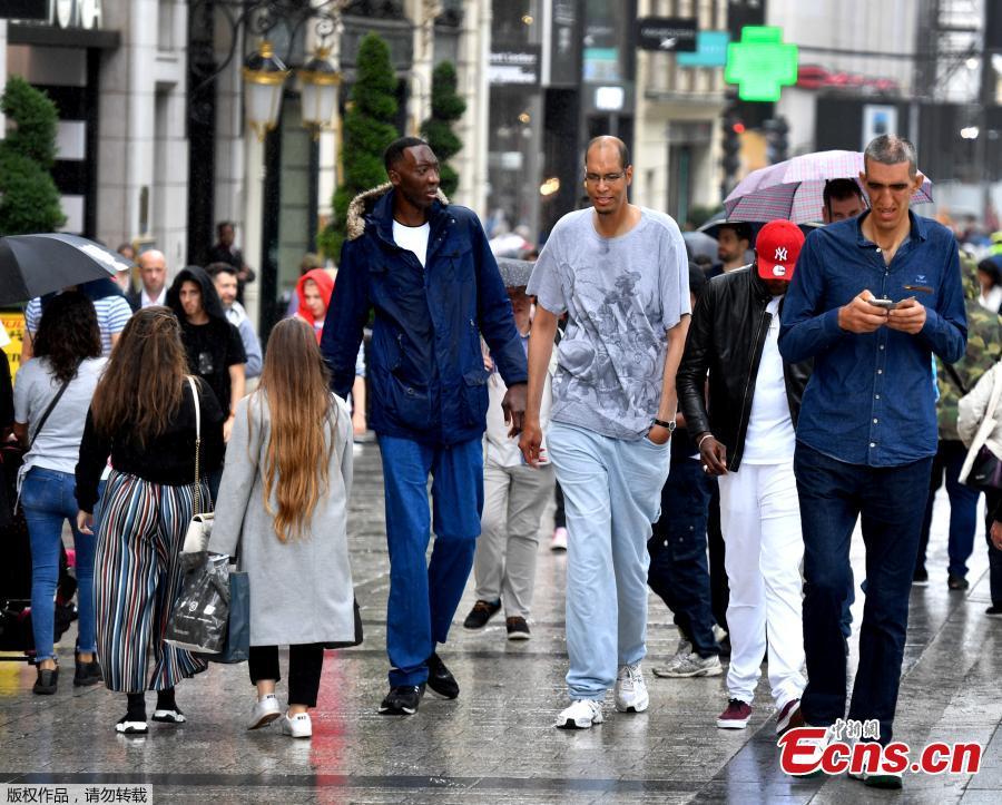 (L to R) Ivory Coast\'s Abdramane Dembele, 2m35, France\'s Brahim Takioullah, 2m46 and Armenia\'s Arshavir Grigoryan, 2m33, walk in the crowd on the Champs-Elysees Avenue in Paris, on June 1, 2018. A dozen of the world\'s tallest people met in Paris for a weekend. (Photo/Agencies)