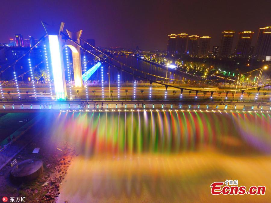 The Xiaolongwan suspension bridge is illuminated by a colorful lighting system in Jiangning District, Nanjing, Jiangsu Province, June 4, 2018. The 1,064-meter-long bridge has become a local attraction thanks to the amazing light show as well as a water spraying system operating from the bridge. (Photo/IC)