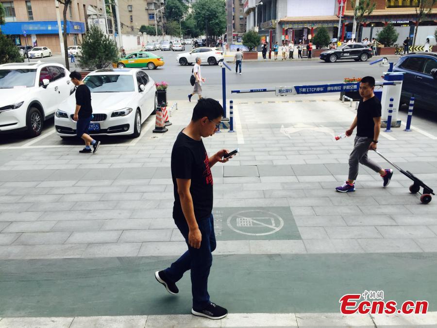 A special lane for phubbers who are busy with phones or mobile devices wherever they go has been built in Xi’an, Northwest China’s Shaanxi Province. The one-meter-wide lane is said to improve safety for those who constantly lower their heads and gaze into the cellphones, but some citizens frown on the idea. (Photo: China News Service/Chen Ying)