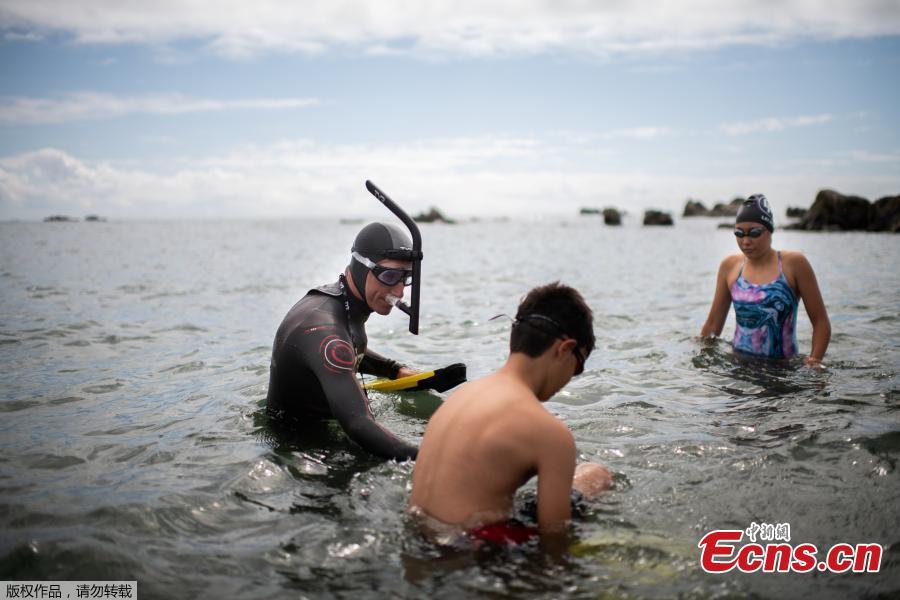French marathon swimmer Benoit \'Ben\' Lecomte (L), takes the start of his attempt of swimming across the Pacific Ocean in Choshi, Chiba prefecture in Japan on June 5, 2018 surrounded by his children, Max (C) and Ana (R). Ben Lecomte dived into the Pacific Ocean on June 5, kicking off an epic quest to swim 9,000 kilometers (5,600 miles) from Tokyo to San Francisco, through shark-infested waters choking with plastic waste. (Photo/Agencies)