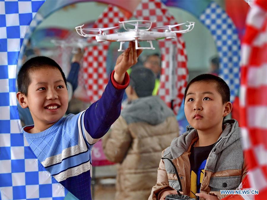 Pupils play with a drone at a primary school in Tangshan of north China\'s Hebei Province, March 15, 2018. Over the last few years, unmanned aerial vehicles (UAVs) have increasingly embedded in everyday life all around China. The duties of these civil drones range from agriculture, transportation to entertainment. The commercial sector relies on unmanned platforms for a variety of services, including aerial photography, crop monitoring, rescuing, delivering and performances. The wide use of drones not only makes life more convenient, but also broadens the imagination of Chinese people towards the coming future. (Xinhua/Yang Shiyao)