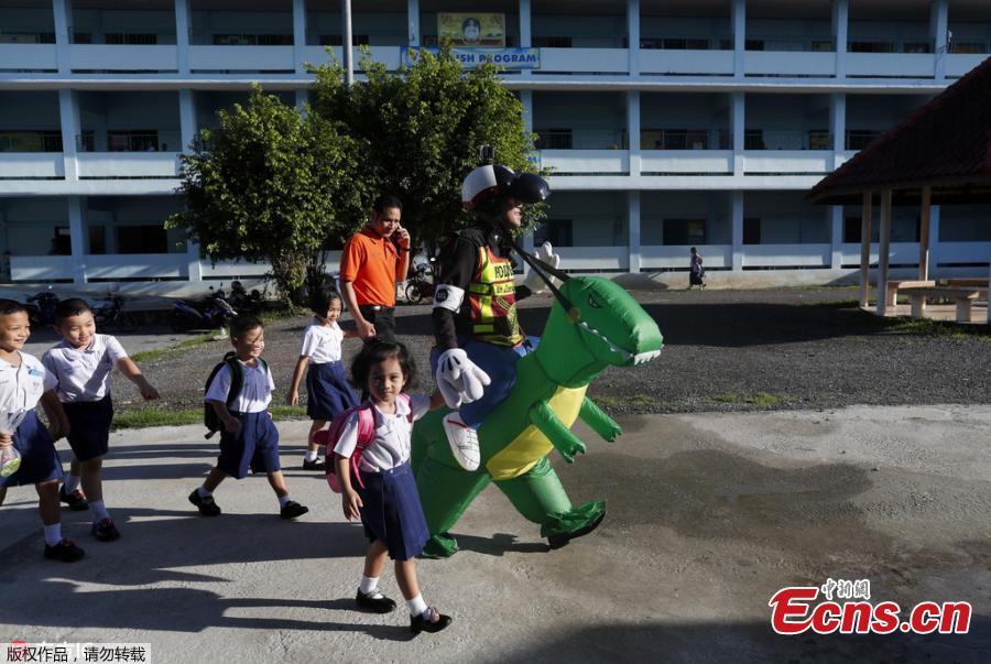 Thai police sergeant Tanit Bussabong directs traffic wearing a costume where he appears to ride a T-rex dinosaur outside a school in Nakhon Nayok on June 4, 2018. Bussabong, who has around 20 different outfits including Minnie Mouse and a bear for his traffic duty outside the kindergarten, said his prehistoric uniform is teaching kids road safety and convincing parents to obey traffic laws.  (Photo/Agencies)
