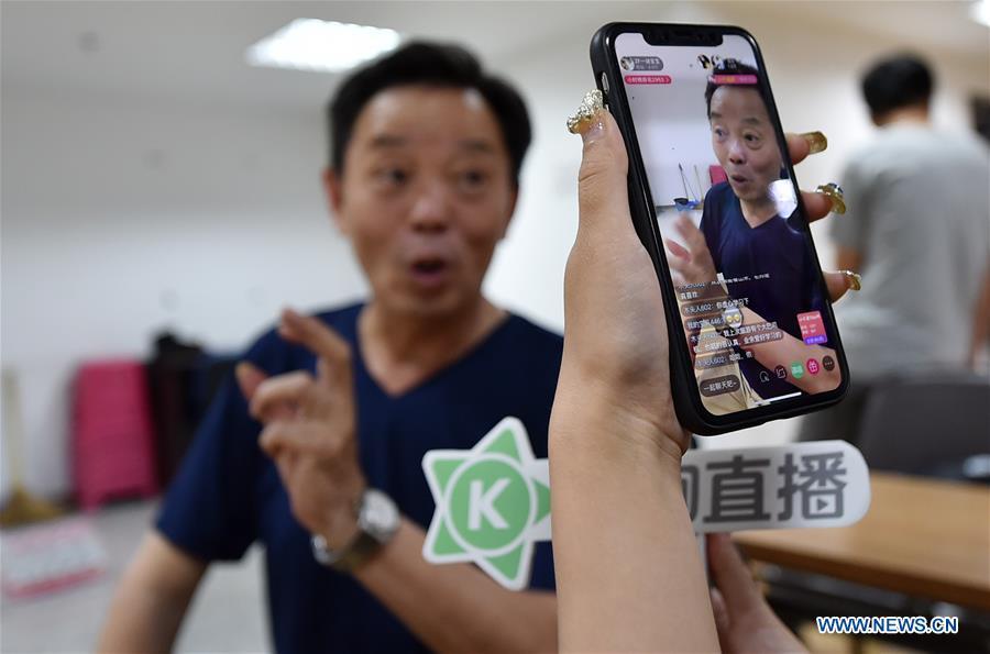 A folk artist communicates with online audience in north China\'s Tianjin Municipality, June 9, 2018. Activities were held around China to celebrate the Cultural and Natural Heritage Day on Saturday. (Xinhua/Li Ran)