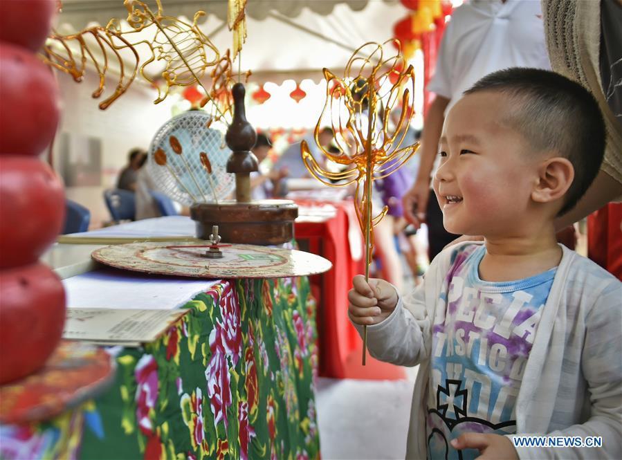 A child gets his sugar painting in an intangible cultural heritage fair in Shenyang, capital of northeast China\'s Liaoning Province, June 9, 2018. Activities were held around China to celebrate the Cultural and Natural Heritage Day on Saturday. (Xinhua/Yao Jianfeng)