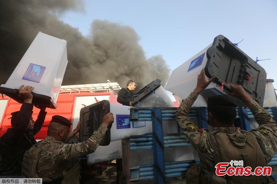 Security forces carry ballot boxes as smoke rises from a storage site in Baghdad, housing the boxes from Iraq\'s May parliamentary election, Iraq June 10, 2018.(Photo/Agencies)