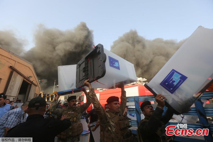 Security forces carry ballot boxes as smoke rises from a storage site in Baghdad, housing the boxes from Iraq\'s May parliamentary election, Iraq June 10, 2018. (Photo/Agencies)