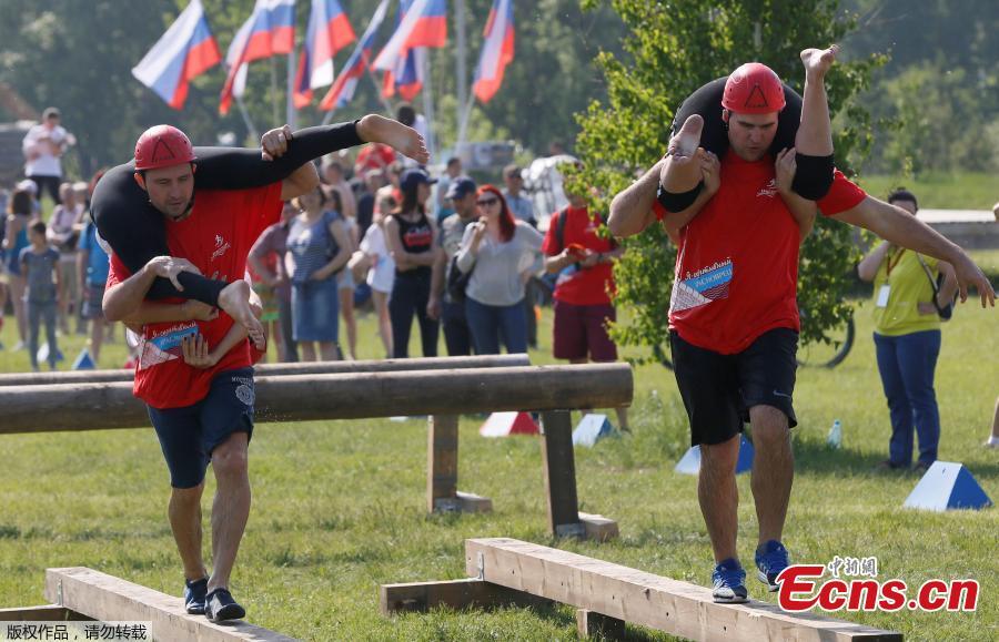 Men carry their wives over an obstacle while racing in the Wife Carrying competition to mark the City Day in Krasnoyarsk, Russia, June 10, 2018. (Photo/Agencies)