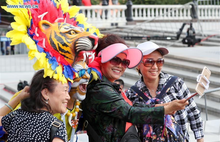 Chinese tourists pose for photos with a Colombian team\'s fan in Moscow, Russia, on June 13, 2018. The 2018 Russia World Cup will kick off on June 14. (Xinhua/Yang Lei)