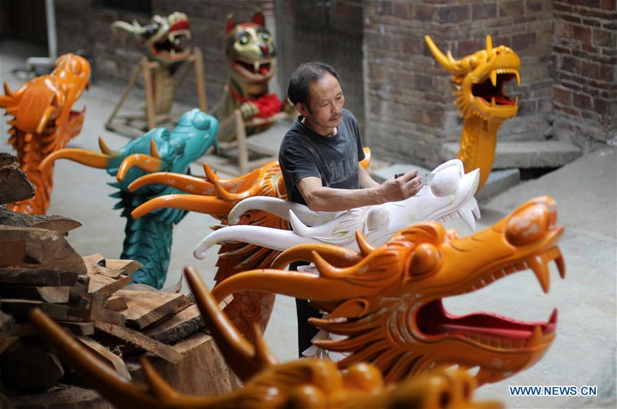 Folk artist Chen Bingshou displays a dragon boat model in Daoxian County of Yongzhou City, central China\'s Hunan Province. Chen, 56, has been engaged in making dragon head for over 40 years. Every year, June is the busiest time for Chen as the demand for the dragon head is strong ahead of the dragon boat festival. Each dragon weighs about 15 kilograms and it takes Chen about 12 days to finish. (Xinhua/He Hongfu)