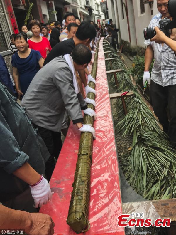 Villagers make a special zongzi - traditionally a pyramid-shaped dumpling made of glutinous rice wrapped in bamboo or reed leaves - to welcome the upcoming Dragon Boat Festival in Qiaoxi Village, Lishui City, East China’s Zhejiang Province, June 12, 2018. It took 50 people nearly 13 hours to make the cylinder zongzi, which was 20.18 meters long and 10 centimeters in diameter, and used 100 kilograms of sticky rice, 20 kilograms of preserved meat and thousands of leaves. (Photo/VCG)