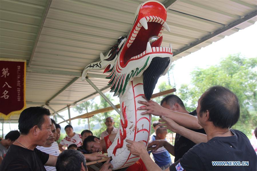 Folk artist Chen Bingshou (1st R) installs the dragon head on the boat with others in Daoxian County of Yongzhou City, central China\'s Hunan Province. Chen, 56, has been engaged in making dragon head for over 40 years. Every year, June is the busiest time for Chen as the demand for the dragon head is strong ahead of the dragon boat festival. Each dragon weighs about 15 kilograms and it takes Chen about 12 days to finish. (Xinhua/He Hongfu)