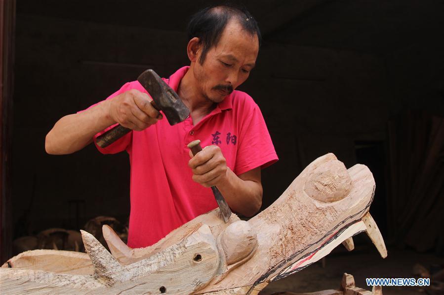 Folk artist Chen Bingshou (1st R) installs the dragon head on the boat with others in Daoxian County of Yongzhou City, central China\'s Hunan Province. Chen, 56, has been engaged in making dragon head for over 40 years. Every year, June is the busiest time for Chen as the demand for the dragon head is strong ahead of the dragon boat festival. Each dragon weighs about 15 kilograms and it takes Chen about 12 days to finish. (Xinhua/He Hongfu)