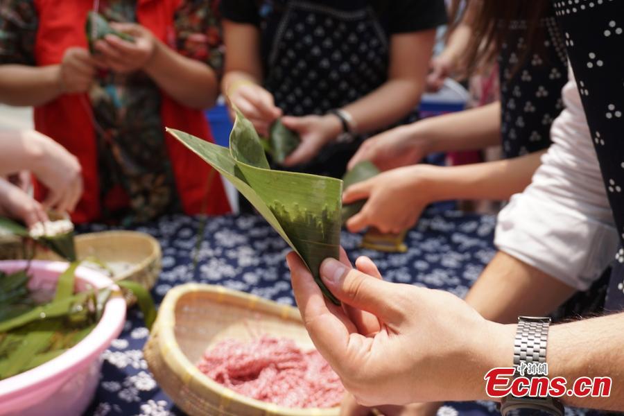 A group of overseas students and expats gathered at Huishan economic development zone in Wuxi, Jiansu Province to learn how to make Zongzi, the palm-sized snack made of glutinous rice wrapped in reed leaves, June 15, 2018, to celebrate the upcoming Dragon Boat Festival. (Photo: China News Service/Sun Quan)