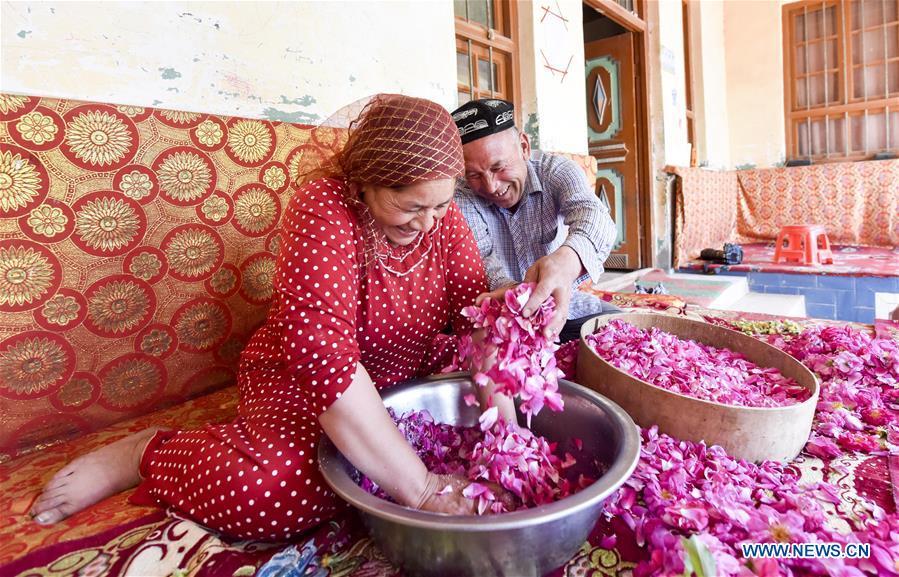 Flower grower Ruz and his wife Tajinisa make rose sauce at a village in Hotan, northwest China\'s Xinjiang Uygur Autonomous Region, June 6, 2018. People in the village are good at making rose sauce, and that is an important source of income for them. (Xinhua/Zhao Ge)