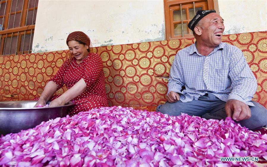 Flower grower Ruz and his wife Tajinisa make rose sauce at a village in Hotan, northwest China\'s Xinjiang Uygur Autonomous Region, June 6, 2018. People in the village are good at making rose sauce, and that is an important source of income for them. (Xinhua/Zhao Ge)