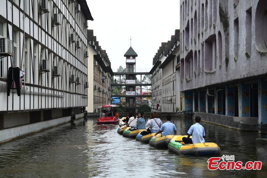 Tourists take boats on an artificial canal during their visit to a wine town in Fuling District, Southwest China’s Chongqing Municipality, June 20, 2018. The five-kilometer-long canal includes a section that passes through a building. (Photo: China News Service/Chen Chao)