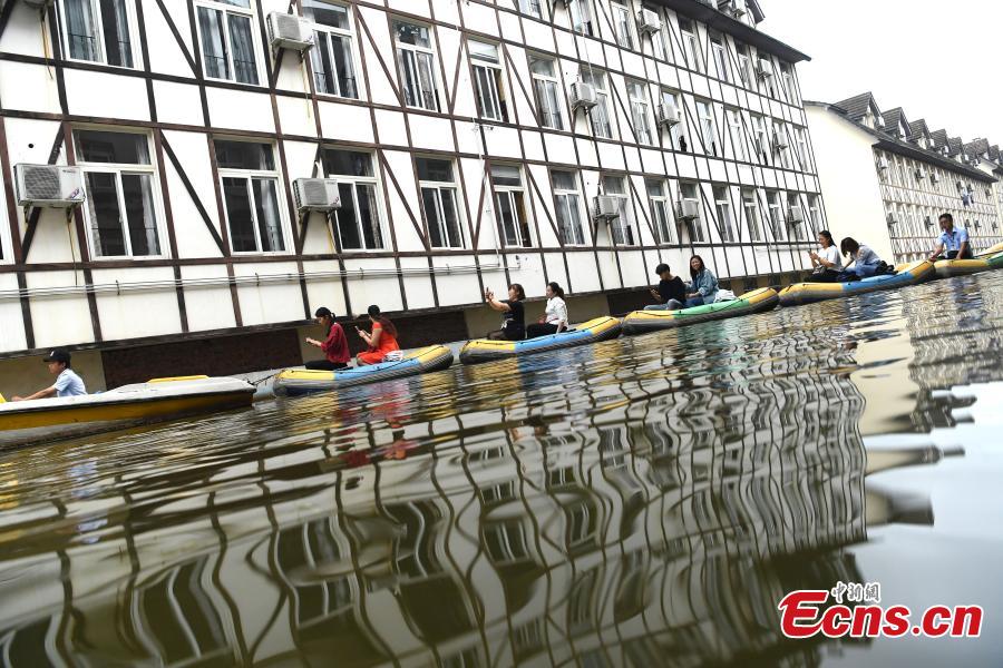 Tourists take boats on an artificial canal during their visit to a wine town in Fuling District, Southwest China’s Chongqing Municipality, June 20, 2018. The five-kilometer-long canal includes a section that passes through a building. (Photo: China News Service/Chen Chao)