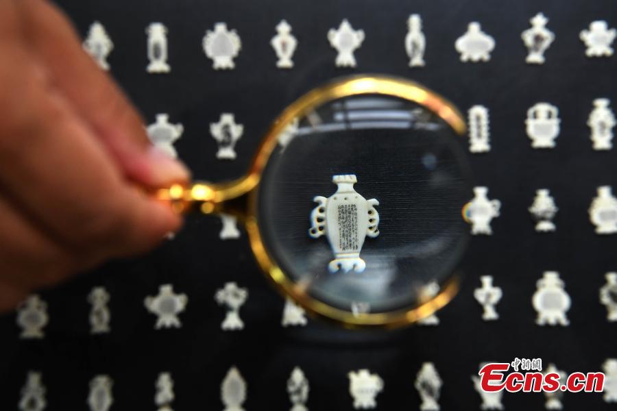 Pan Qihui shows miniature calligraphy he carved at an exhibition in Chongqing, June 23, 2018. The smallest characters carved by Pan are as thin as a hair and a magnifying glass is needed to see them. (Photo: China News Service/Chen Chao)