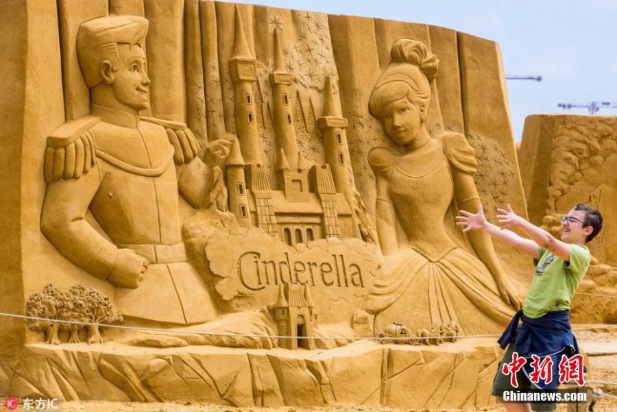 A visitor takes photos beside a sculpture during the Sand Sculpture Festival \