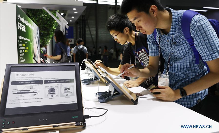 Visitors try out electronic ink devices during the Mobile World Conference Shanghai (MWCS) 2018 in east China\'s Shanghai, June 27, 2018. The three-day MWCS 2018 kicked off at the Shanghai New International Expo Center on Wednesday, showing trending mobile products, services and technologies. (Xinhua/Fang Zhe)