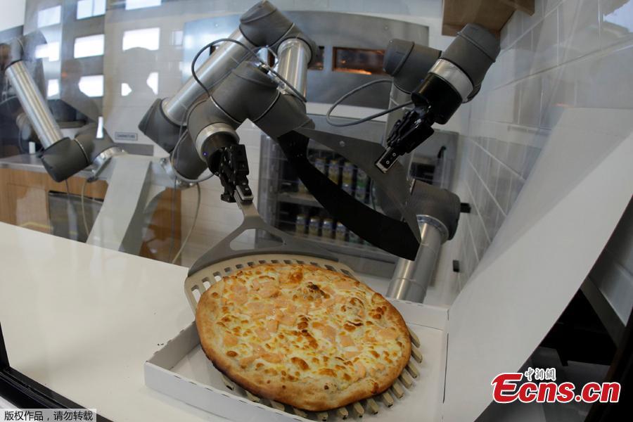 A pizzaiolo robot places a cooked pizza into its box before the customer’s eyes at the showroom of French food startup EKIM in Montevrain near Paris, France, June 26, 2018. Picture taken June 26, 2018. (Photo/Agencies)