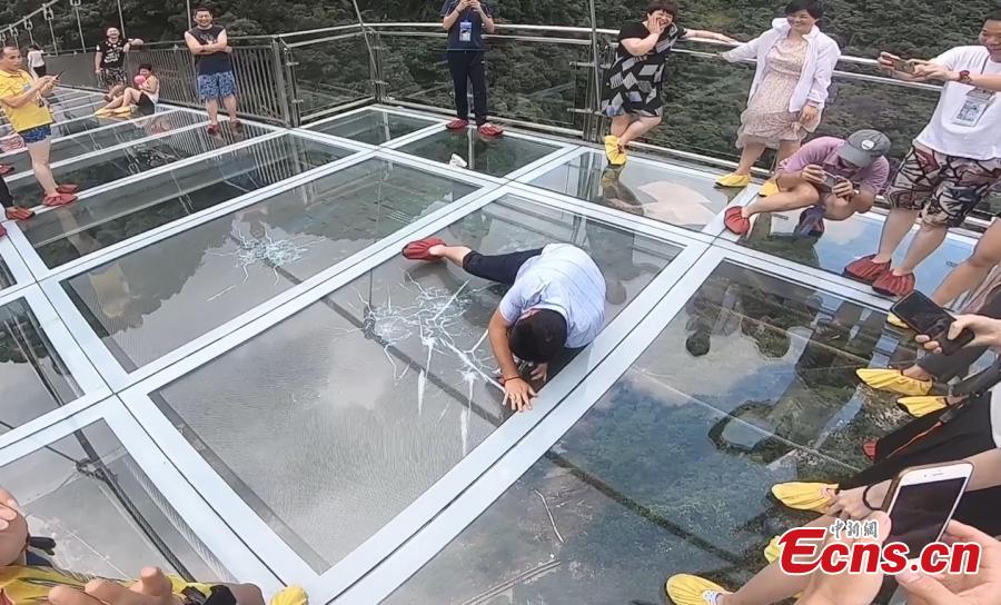 Tourist look at fake cracks on a vertigo-inducing glass bridge suspended over a valley in Qingyuan City, South China’s Guangdong Province, June 28, 2018. The structure also features a massive circular glass observation deck suspended at the end of the bridge, jutting out 72 meters from the cliff edge. (Photo: China News Service/Xu Qingqing)