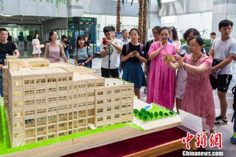 Visitors look at a chopsticks-made model of the library of China Three Gorges University in Yichang City, Central China’s Hunan Province, June 28, 2018. (Photo: China News Service/Yu Dongshan)