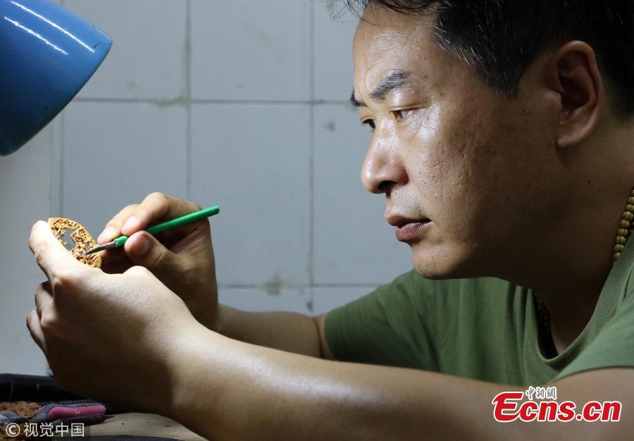 Folk artist Liu Jun, also a football fan, carves a peach pit in his home in Jining City, East China’s Shandong Province, July 1, 2018. Liu’s latest World Cup-inspired creation depicts six players competing on a coin-sized peach pit. Liu said he often stayed up late to watch the World Cup matches. (Photo/VCG)