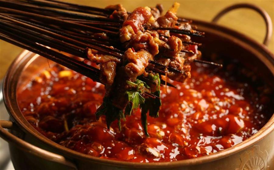 Chuanchuanxiang is a hot pot that cooks ingredients on skewers/sticks. (Photo/Shine.cn)

Chuanchuanxiang

Cooked and served in skewers, chuanchuanxiang can be described as one form of hotpot, or mini hotpot as some people call it. The word chuanchuan means sticks/skewers.

Originating in Chengdu, this spicy delicacy cooks all kinds of vegetable and meat skewers in hot spicy broth, just like hotpot but with skewers, and the cost of the meal is calculated by counting the number of skewers.

The chuanchuanxiang broth is filled with herbs and spices to elevate the depth of flavor, like caoguo (Amomum tsao-ko), fennel, baidoukou (Amomum kravanh), cloves and star anise. One can choose spicy or original broth, which has the same base of chicken or pork stock but different kinds and amount of seasonings.

Beef, shrimp, tofu and vegetables are the basic ingredients in chuanchuanxiang, and offal such as chicken heart, duck intestine and beef tripe are what makes a meal complete and authentic. When cooked in the spicy broth, the not-so-appetizing offal parts become mouthwatering delicacies.

Like hotpot, chuanchuanxiang is served with dipping sauces on the side. The traditional Sichuan flavor is made of a bowl of sesame oil-based sauce and a plate of dry ground chilies, toasted white sesame seeds and crushed peanuts.