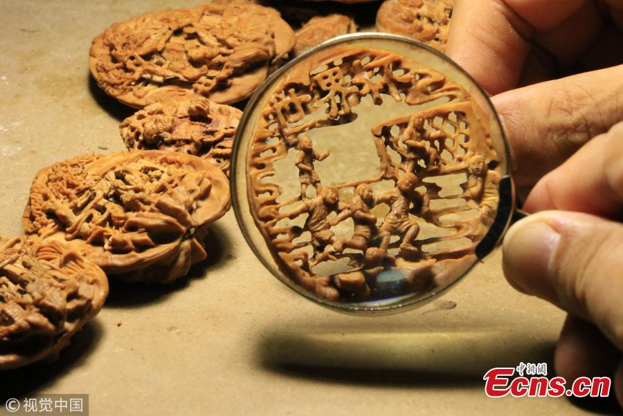 Folk artist Liu Jun, also a football fan, shows a peach pit creation in his home in Jining City, East China’s Shandong Province, July 1, 2018. Liu’s latest World Cup-inspired creation depicts six players competing on a coin-sized peach pit. Liu said he often stayed up late to watch the World Cup matches. (Photo/VCG)