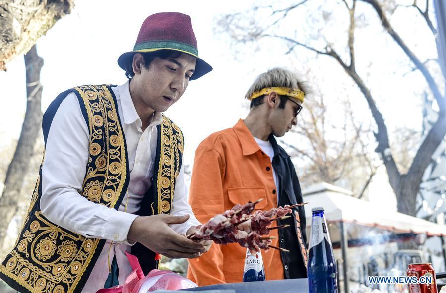 Daodao (L) makes grills when filming a music video in Urumqi, northwest China\'s Xinjiang Uygur Autonomous Region, March 30, 2018. (Xinhua/Wang Fei)