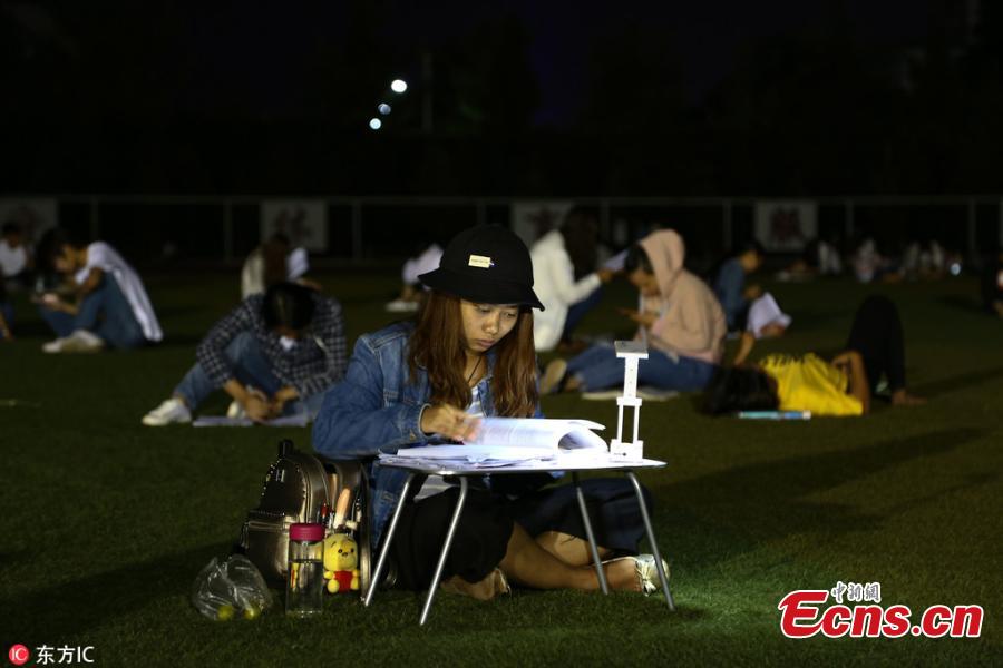 Students prepare for semester final exams on the football field of Qujing Medical College in Southwest China’s Yunnan Province, July 4, 2018. Students used flashlights on their mobile phones, small chargeable table lamps, and the lights of the football field to help them revise outside on what was a hot summer night. (Photo/IC)