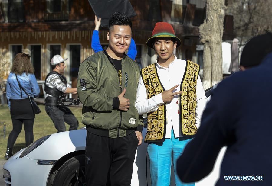 Daodao (R) poses for pictures with his fan when filming a music video in Urumqi, northwest China\'s Xinjiang Uygur Autonomous Region, March 30, 2018. (Xinhua/Wang Fei)