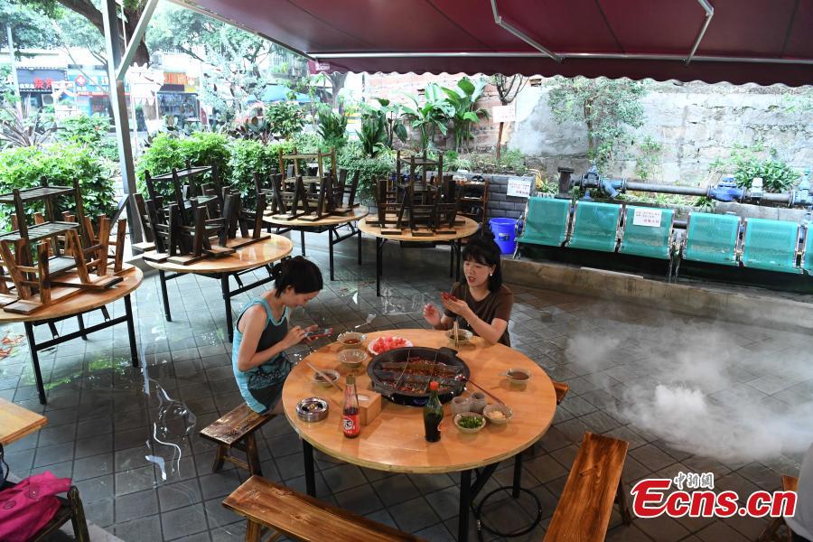 Diners enjoy hotpot while dipping their feet in a pool at a restaurant in Chongqing, July 5, 2018. Gold fish are kept in the pool, which allows customers to enjoy a footbath while eating the popular stew, a hot meal mixed with meat and vegetables. (Photo: China News Service/Chen Chao)