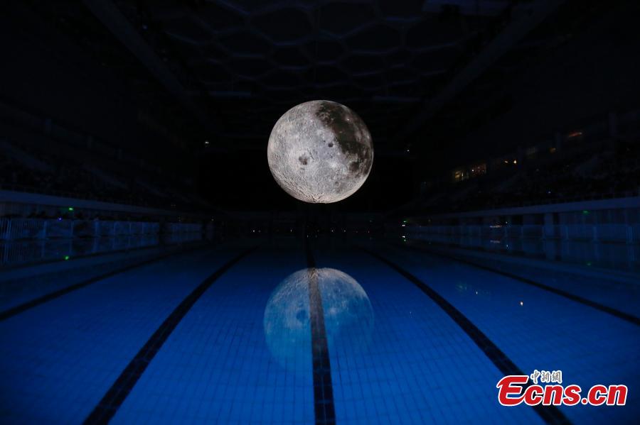 Visitors take photos of a huge moon model during an exhibition on moon held at the National Aquatic Center or \