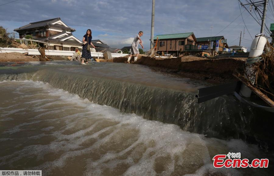Residents cross an area still flooded in Kurashiki, Okayama prefecture on July 9, 2018.
The death toll from widespread flooding and landslides rose to 126, according to Japanese authorities.  (Photo/Agencies)