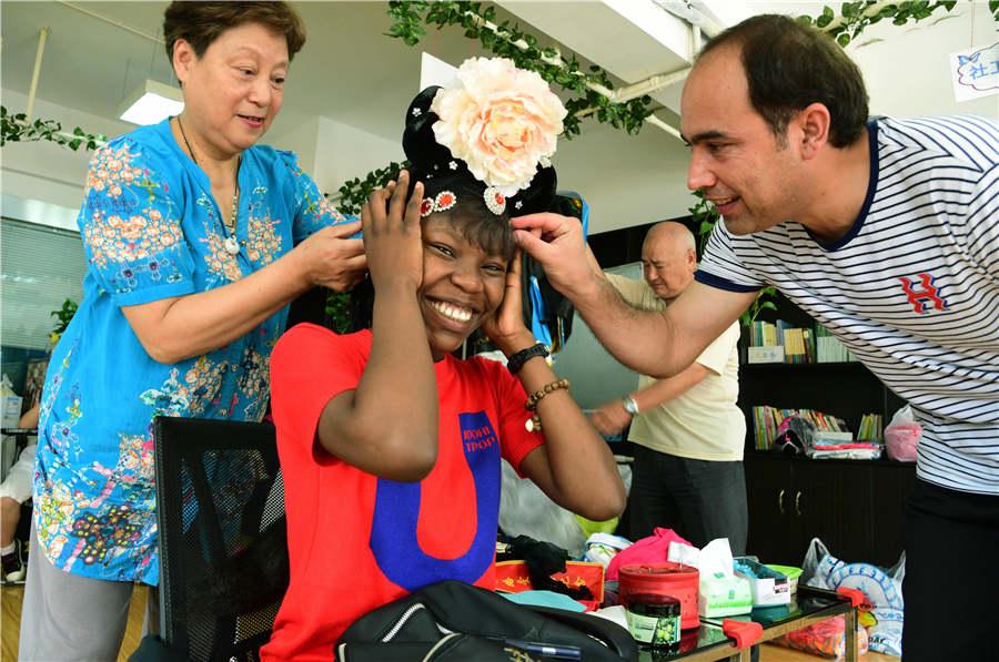 A teacher applies facial makeup to a foreign student in Zhenjiang city, Jiangsu Province, on July 9, 2018.  (Photo/Asianewsphoto)