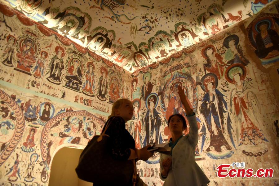 Visitors look at the Digital Dunhuang - Tales of Heaven and Earth exhibition at the Hong Kong Heritage Museum, July 10, 2018. Jointly presented by the Hong Kong Leisure and Cultural Services Department and the Dunhuang Academy, the exhibition highlights the achievements of digitization projects at the Dunhuang Academy, together with a presentation of unearthed artefacts, the grotto art of Dunhuang, and the latest multimedia technology. The Dunhuang Academy has made substantial achievements in digitization, 3D scanning and virtual reality representation of the Dunhuang relics. (Photo: China News Service/Zhang Wei)