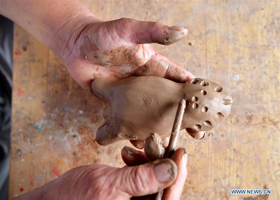 <?php echo strip_tags(addslashes(Local handicraftsman Ren Guohe makes a clay statuette in Jinzhuang Village of Huaiyang County, central China's Henan Province, July 9, 2018. Originated from ancient sacrificial ceremonies, the hand-made clay statuette 