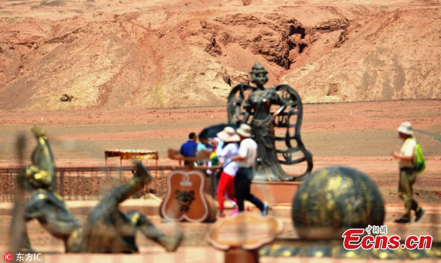 People visit the Flame Mountain Scenic Area in Turpan, Xinjiang Uygur Autonomous Region, July 10, 2018. More than 2,000 tourists a day flocked to the scenic area, 40 kilometers away from downtown Turpan, to challenge the extreme heat. (Photo/IC)