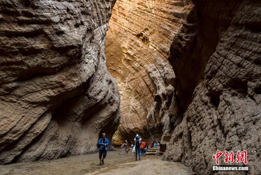 Visitors look at Kuqa Gorge, located to the south of Tianshan Mountain and about 60 kilometers to the north of Kuqa county in Aksu, Xinjiang Uygur Autonomous Region, July 10, 2018. Kuqa Gorge is made up of huge red mountains which are called \
