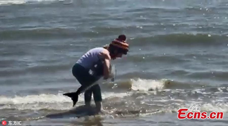 Jenni Hanninen, from Finland, is seen in action saving a baby dolphin stranded on Seapoint beach in Louth, Ireland on June 30, 2018. She was out horse riding on Seapoint Beach with two friends when they spotted the animal washed up on the shore. Jenni picked up the mammal and carried it out to the water before releasing it into the wild once again. (Photo/IC)