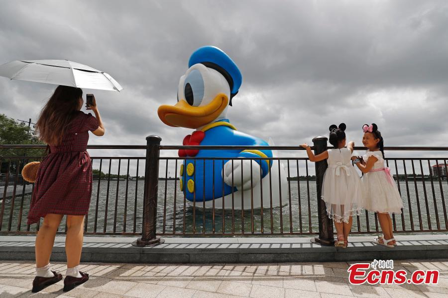 <?php echo strip_tags(addslashes(Visitors pose for photos with an 11-meter-tall Donald Duck in Wishing Star Lake at the Shanghai Disney Resort, July 12, 2018. (Photo/China News Service))) ?>