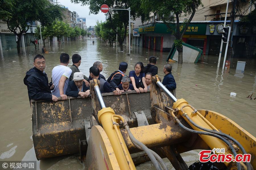 A bulldozer transports people on a flooded street in Jintang County, Southwest China’s Sichuan Province, July 12, 2018, after heavy rain. (Photo/VCG)