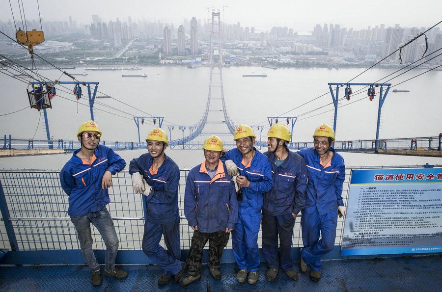 Workers from the China Railway Major Bridge Engineering Group Wen Yuanke, Feng Kui, Hu Guiming, Chen Fei, Shuare Ribu, Lai Shiliang on the construction platform (left to right).[Photo/Xinhua]

The Yangsi Port Yangtze River Bridge is a double-tower, double-layer anchored steel truss girder highway suspension bridge with a main span of 1,700 meters. Upon completion, it will be the world\'s largest double-deck suspension bridge.