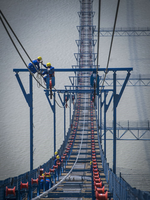 Liu Neng, 34, from Luzhou, Sichuan province, works with a fellow worker at high altitude.[Photo/Xinhua]